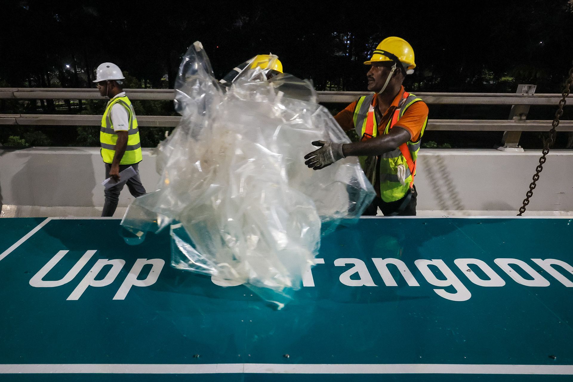 Workers remove the protective plastic sheets covering the signs and conduct a final visual inspection.