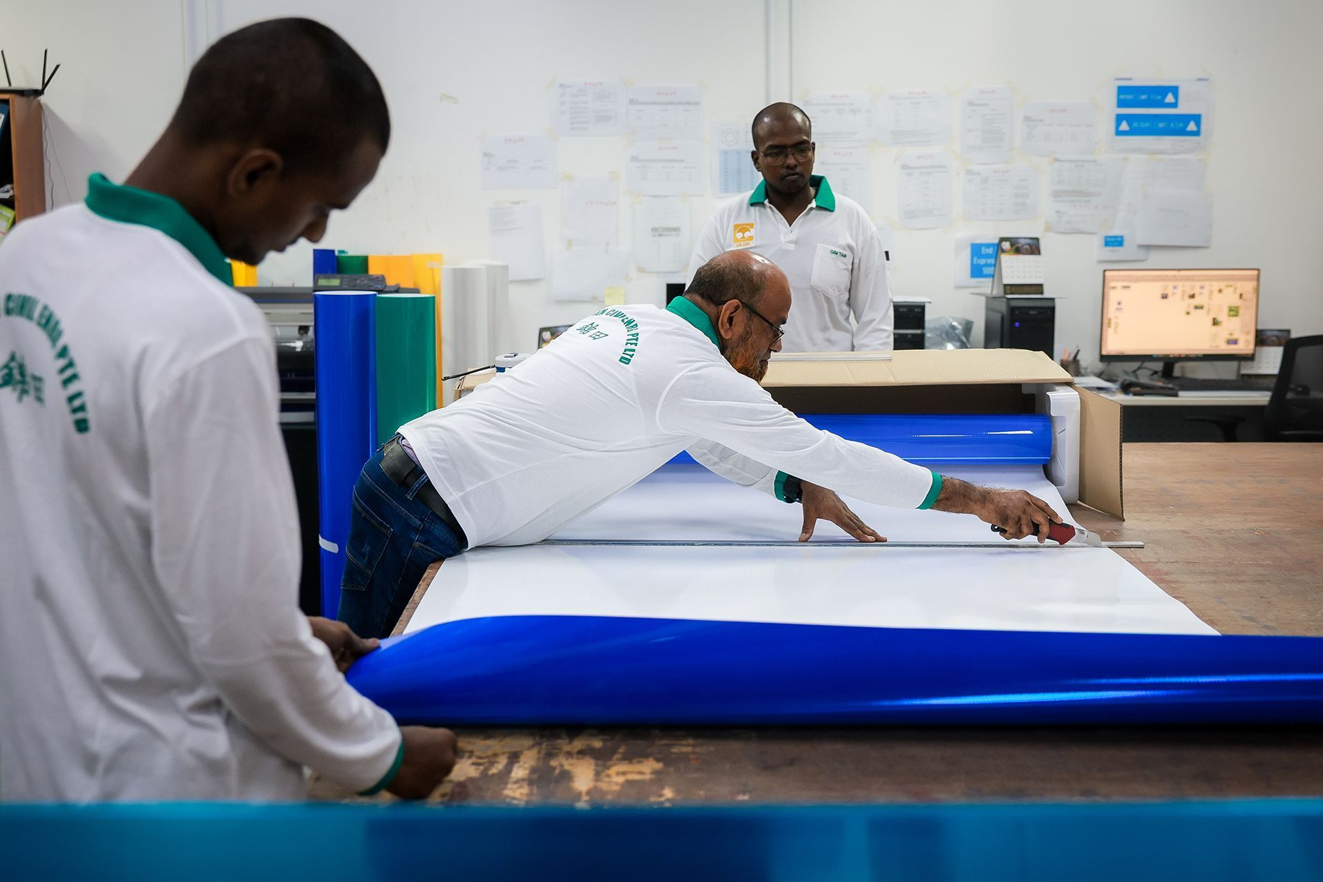 A worker uses a penknife to cut retroreflective films.