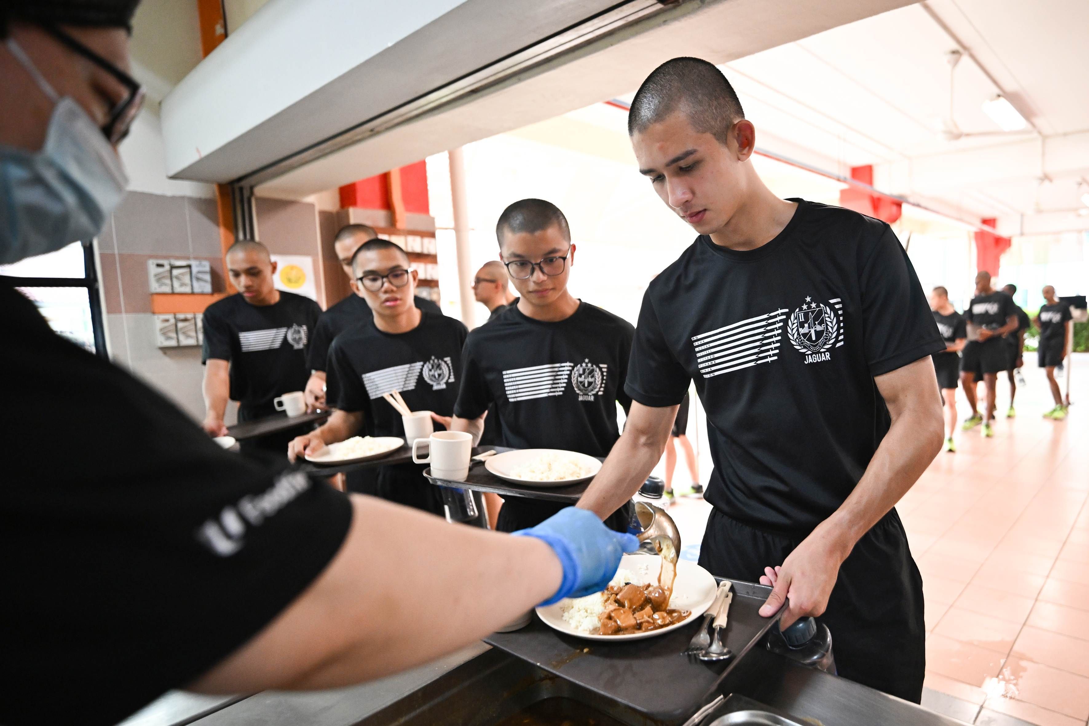 A group of men line up for food at the Basic Military Training Centre on Pulau Tekong.