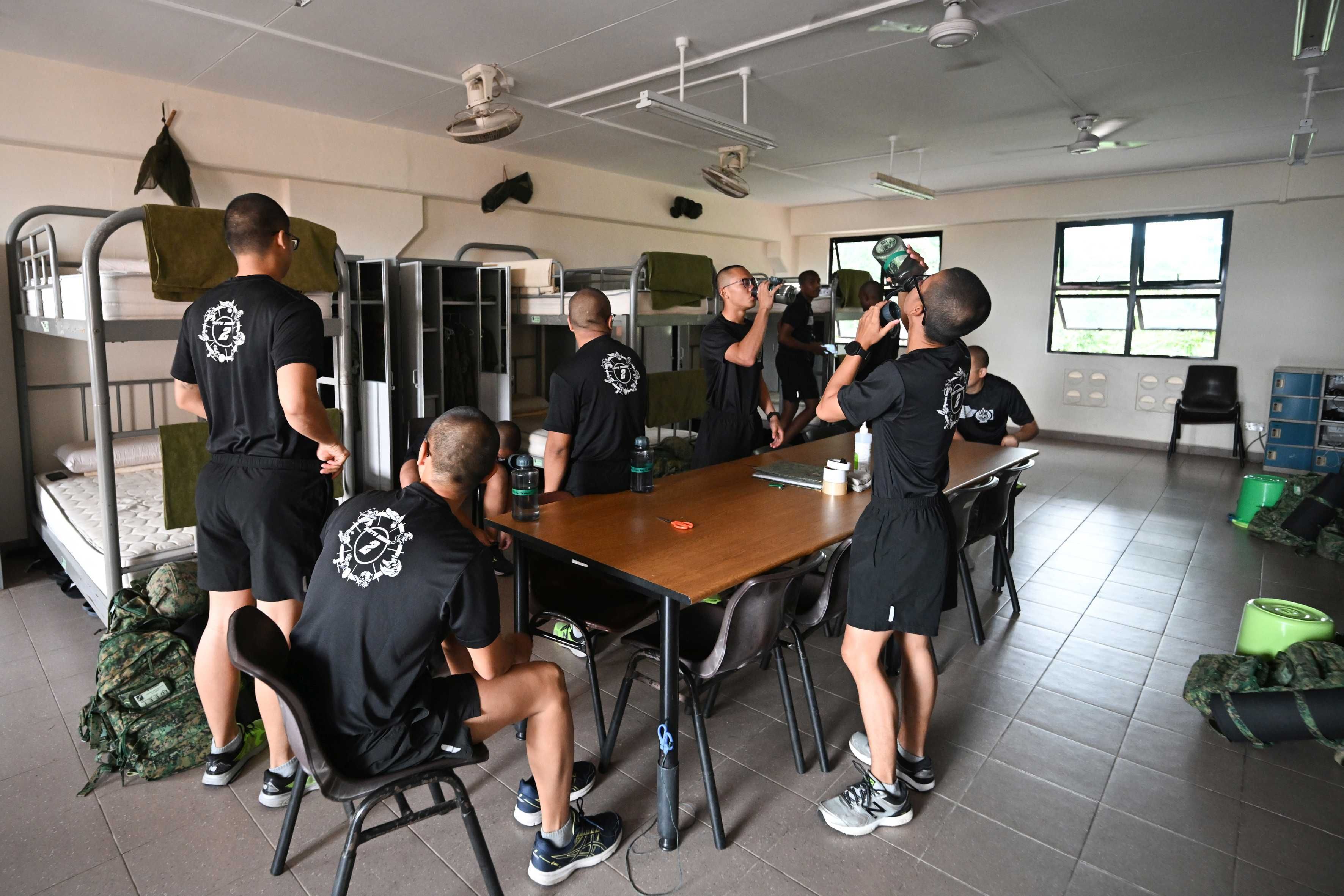 A group of men gather around bunk beds in a room at the Basic Military Training Centre on Pulau Tekong.