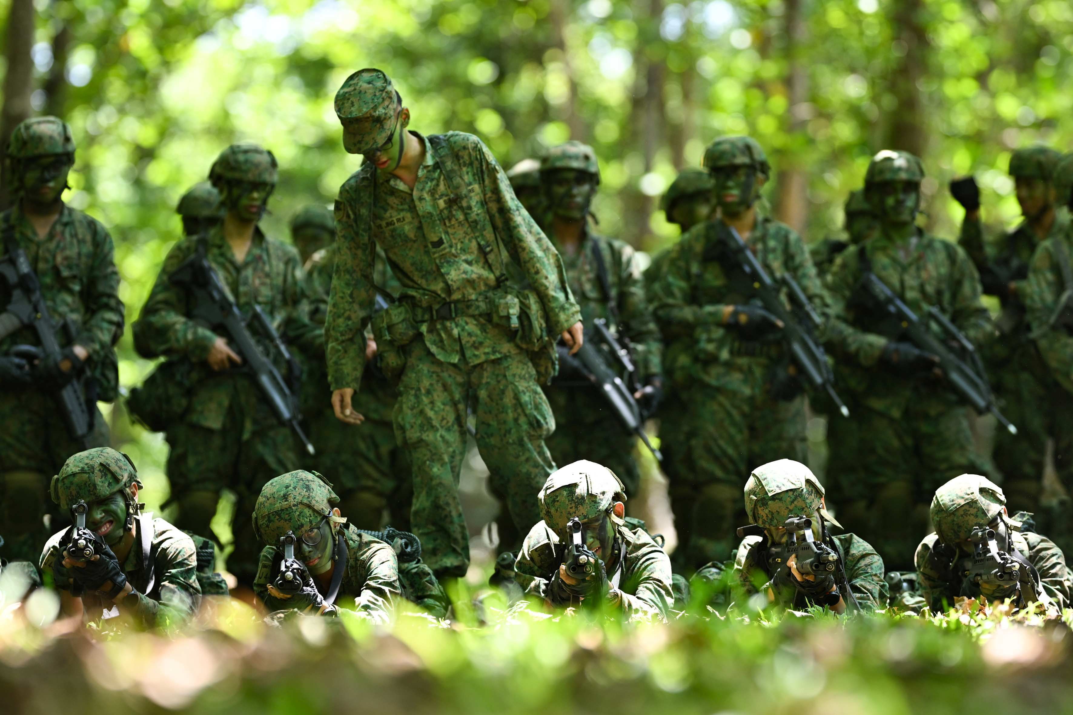 A group of men using rifles during a military training exercise at the Basic Military Training Centre on Pulau Tekong.