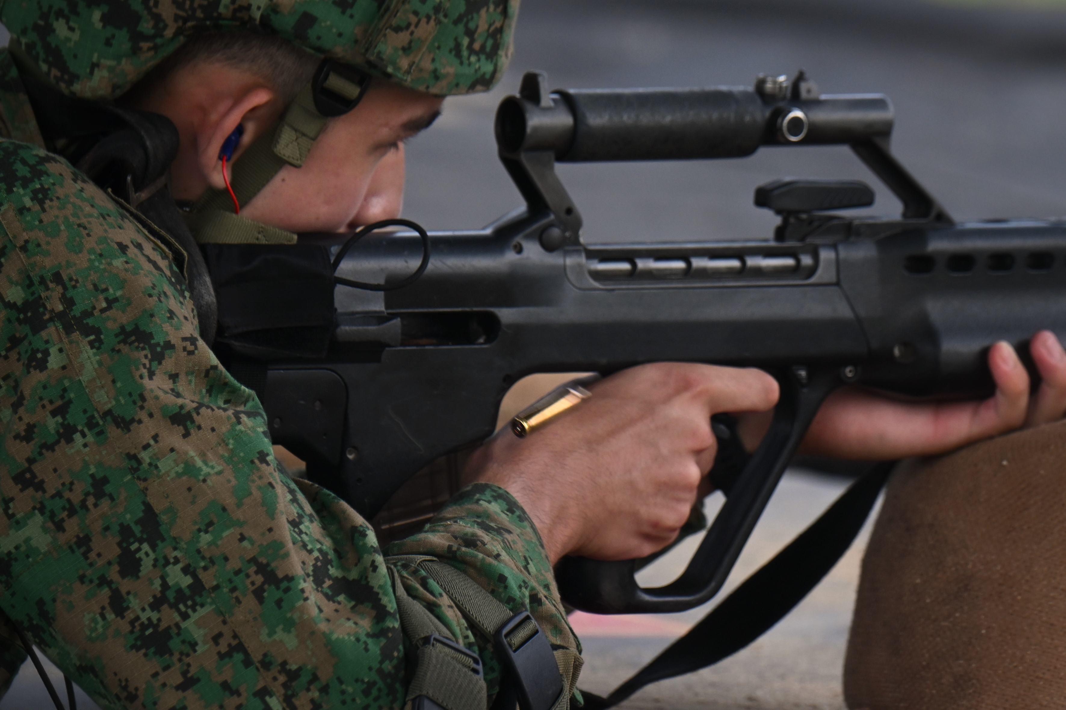A spent cartridge case is ejected while a man fired his rifle during a training exercise at the Basic Military Training Centre in Pulau Tekong.