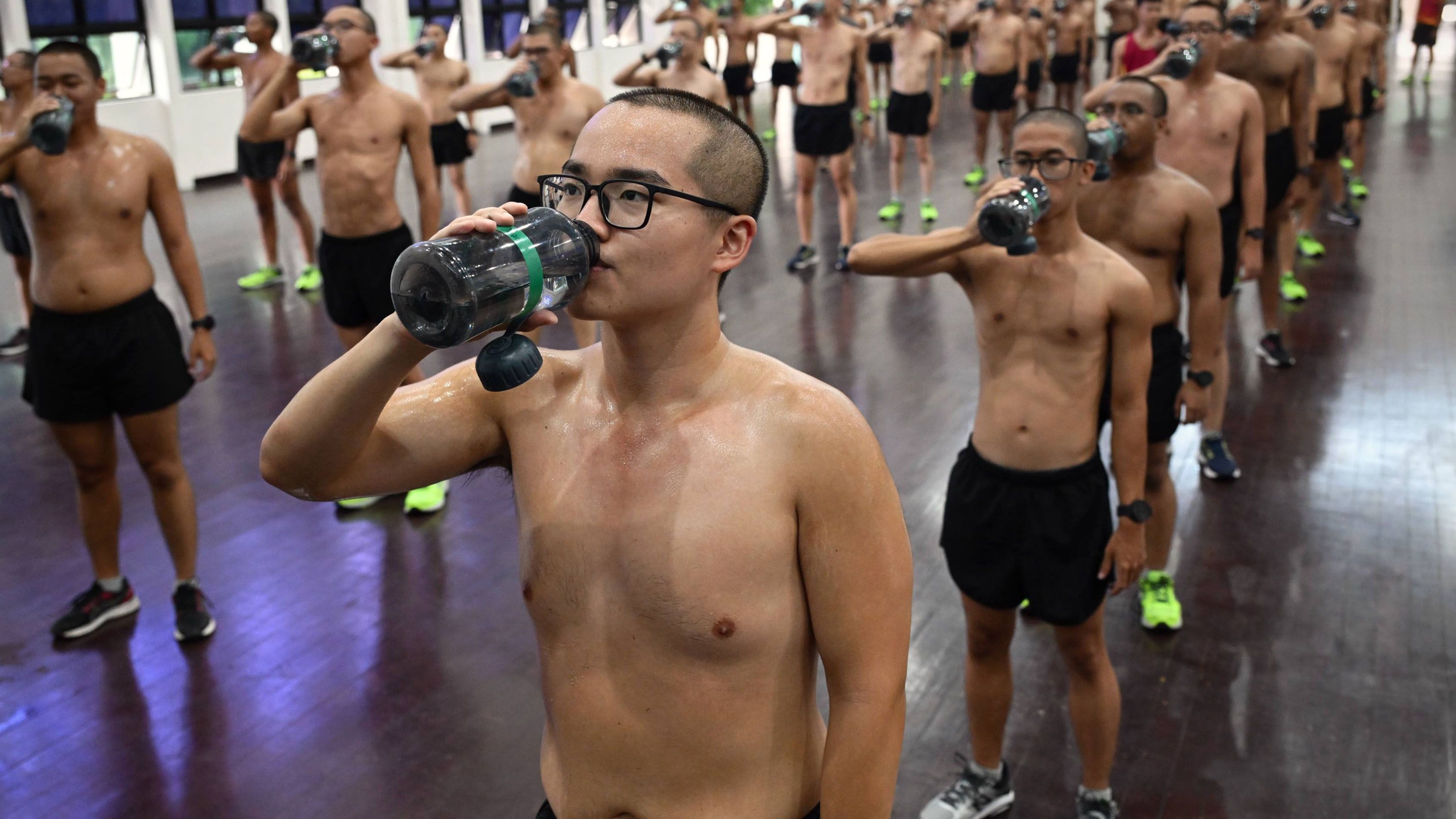 Person drinking from a water bottle after doing exercises