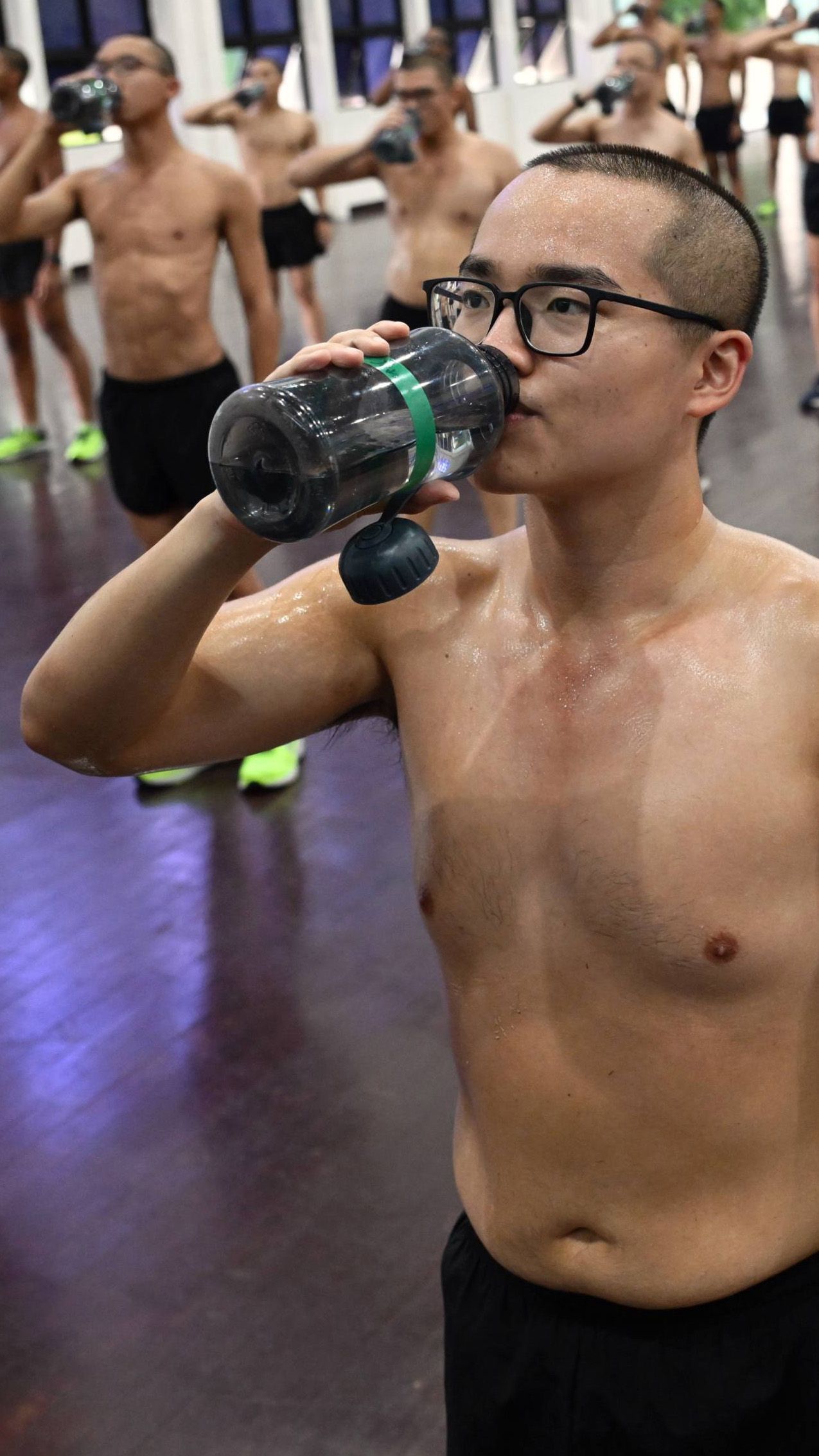 Person drinking from a water bottle after doing exercises